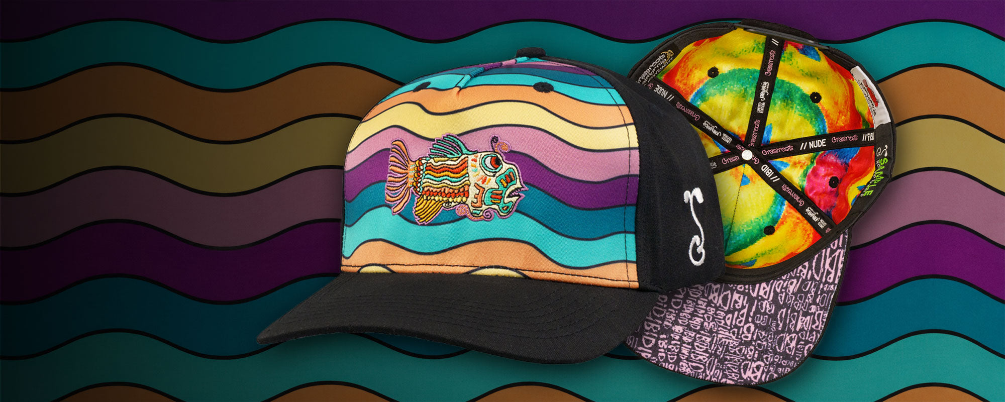 A black baseball cap with a colorful psychedelic wavy stripe pattern on the front and an embroidered fish, shown alongside the back of another cap featuring a colorful floral pattern. The background is a wavy multicolor pattern.